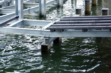 Metal rıhtım iskeleti dalgalanan karanlık su yüzeyinin üzerine uzanıyor