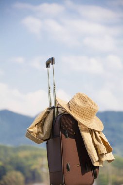 Dağ manzarası, seyahat ve turizm konseptine karşı hasır şapkalı ve ceketli bavul