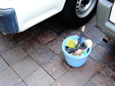 Mavi kovada çeşitli araba temizleme malzemeleri var.