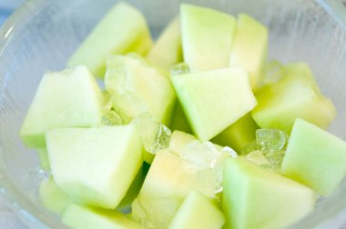 Taze yeşil meyve dilimleri kasede buzla, yakın plan.