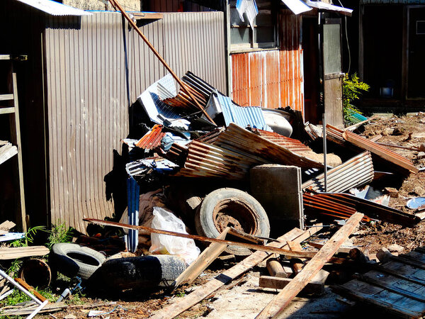 Rusted metal debris scattered near abandoned wooden sheds outdoors