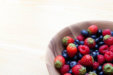 Taze yaban mersini, çilek ve ahududu. Tahta kasede organik meyveler