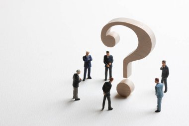 Minyatür iş adamları ve beyaz arkaplanda tahta soru işareti