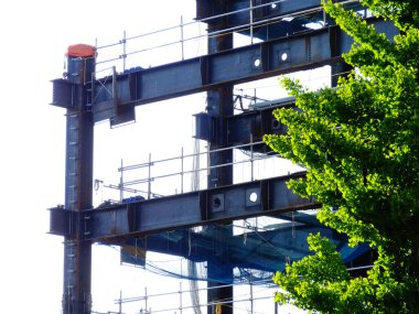 Çelik yapı iskeleler ve yeşil ağaçlarla çevrili.