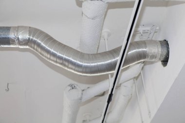 Beyaz tavan boruları ve duvarlar boyunca uzanan metal kanal işi.