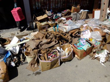 Güneşli caddeye saçılmış çeşitli çöp ve mukavva yığınları