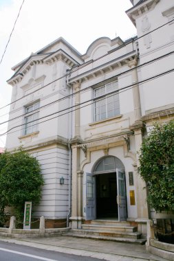 Üzerinde kemerli kapı ve geniş pencereler bulunan tarihi beyaz bina