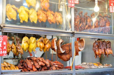 Meşgul pazarda kızarmış ördekler, tavuklar ve etler sergileniyor