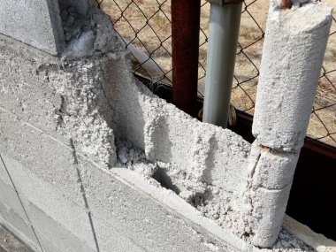 Hasarlı beton duvar çatlakları ve açıkta kalan demiri gösteriyor.