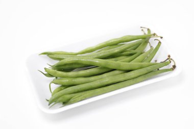 Beyaz plaka üzerindeki yeşil fasulyeler beyaz arkaplanda izole edilmiş 