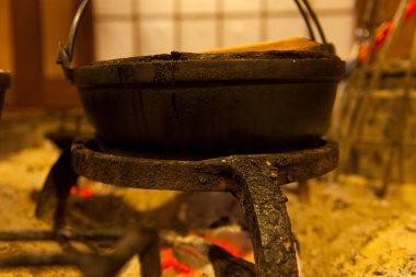 Parlayan közlerin üzerinde asılı olan taşralı demir tencere.