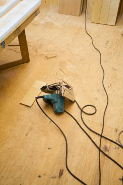 Kablolarla çevrili tahta zeminde duran elektrikli bir alet.