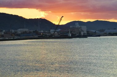 Arka planda dağlarla birlikte gün batımı liman üzerinde