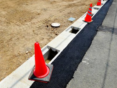 Yol inşaatı detayları, parlak turuncu trafik konileri.