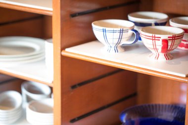 Ahşap raflarda renkli bardaklar ve tabaklar