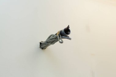 Beyaz boyalı duvar yüzeyinden çıkan açığa çıkmış elektrik kabloları