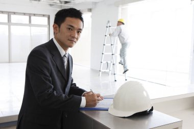 Beyaz kaskın yanında duran bir iş adamı.