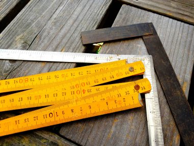 Katlanan cetvel ve metal meydan dışarıda tahta tahtalarda dinleniyor.