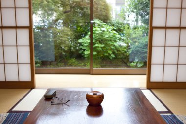 Sunlit Japon tatami odası, bahçeye bakan ahşap masa.
