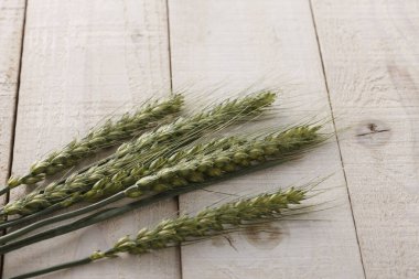 Ahşap masa arkasında taze yeşil buğday kulakları