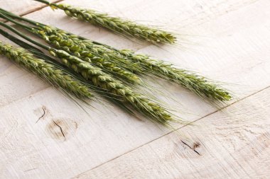 Ahşap masa arkasında taze yeşil buğday kulakları