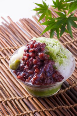 Arka planda haşlanmış azuki fasulyesi ve erikli Matcha buzu, yakın plan.