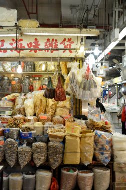 Kurumuş ürünlerin parlak ışıkların altında asılı olduğu renkli bir market tezgahı.