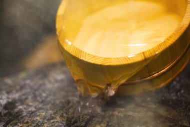 Tahta kase taşlara su döküyor.