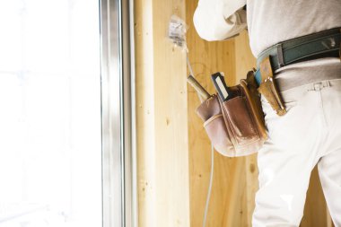 Üniformalı adam evin duvarında çalışıyor.