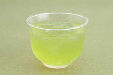 Temiz plastik bardakta yeşil içecek tazeleniyor.