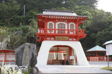 Geleneksel Japon binası yeşillik ve taşla çevrili.