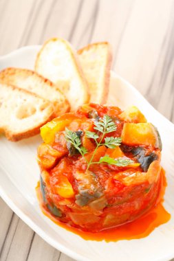 Bir tabak sebze yahnisi ve dilimlenmiş ekmek. 