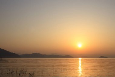 Manzaralı tepeler ve göl üzerinde güzel gün batımı       