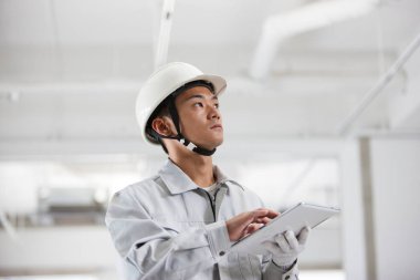 İnşaat alanındaki yakışıklı genç Asyalı mimarın portresi.