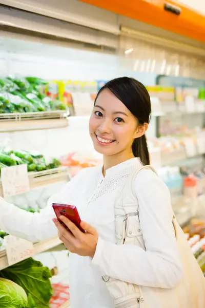 Sorrindo Mulher Japonesa Com Compras Smartphones Supermercado Verificando Lista Compras — Fotografia de Stock