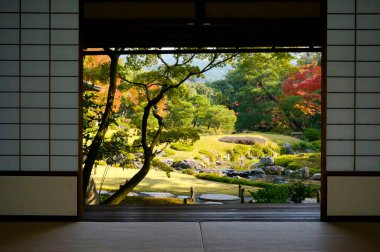 Geleneksel bir Japon bahçesi manzarası, bir Japon evinin içinden sürgülü kapılar (Shoji veya fusuma) kullanılır.).