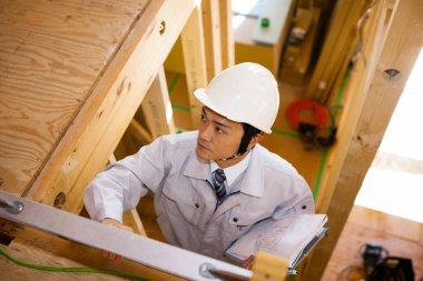 Ahşap binayı inceleyen Asyalı genç inşaat müfettişinin portresi.