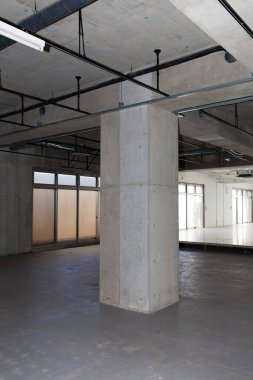 Gri duvarları ve boruları olan endüstriyel yapı.         