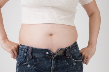 Genç şişman kadın beyaz arka planda göbeğini gösteriyor.