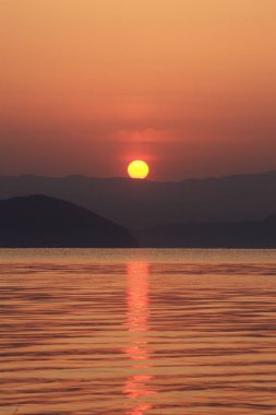 Ufuktaki tepelerle gölün üzerinde güzel bir günbatımı        