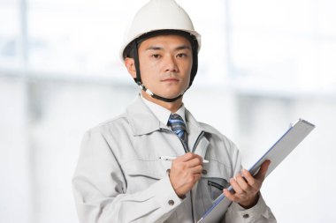 İnşaatta üniformalı yakışıklı Asyalı mühendis.