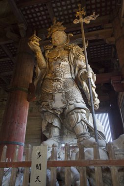 Japon tapınağındaki antik heykelin manzaralı resmi.