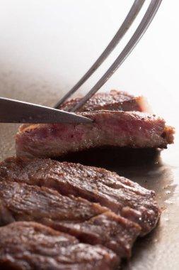 Çatal ve bıçakla kesilmiş taze bifteğin yakın plan görüntüsü                          