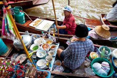 Satıcılar yüzen teknelerde yiyecek satıyorlar.