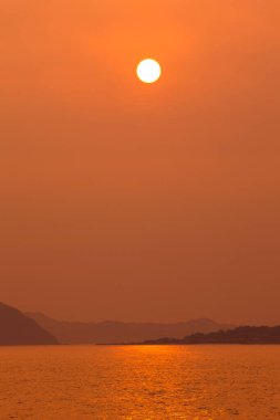 Denizin ve tepelerin üzerinde güzel gün batımı