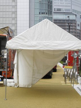 Modern binaların arasında beyaz gölgelik çadır var.