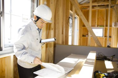 Ahşap binayı inceleyen Asyalı genç inşaat müfettişinin portresi.