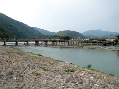 Yeşil dağlarla çevrili köprünün altından akan nehir.