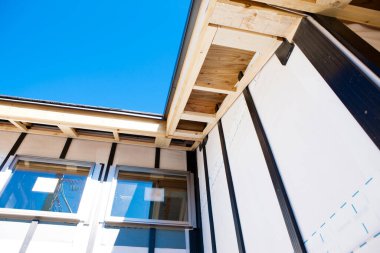 Ahşap kirişler ve mavi gökyüzü ile bina köşesini gösteriyor