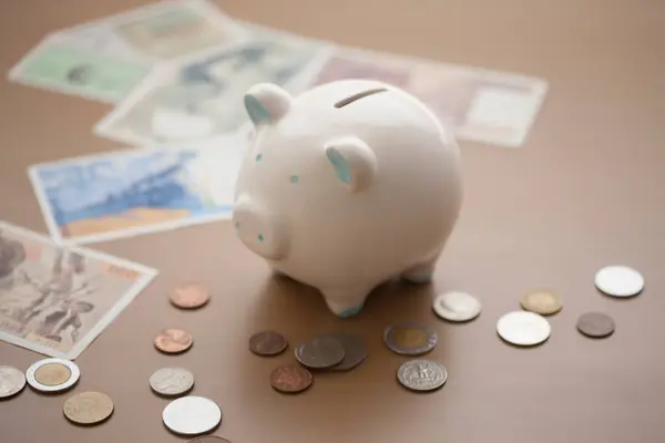 piggy bank, banknotes and coins on table, saving money for the future